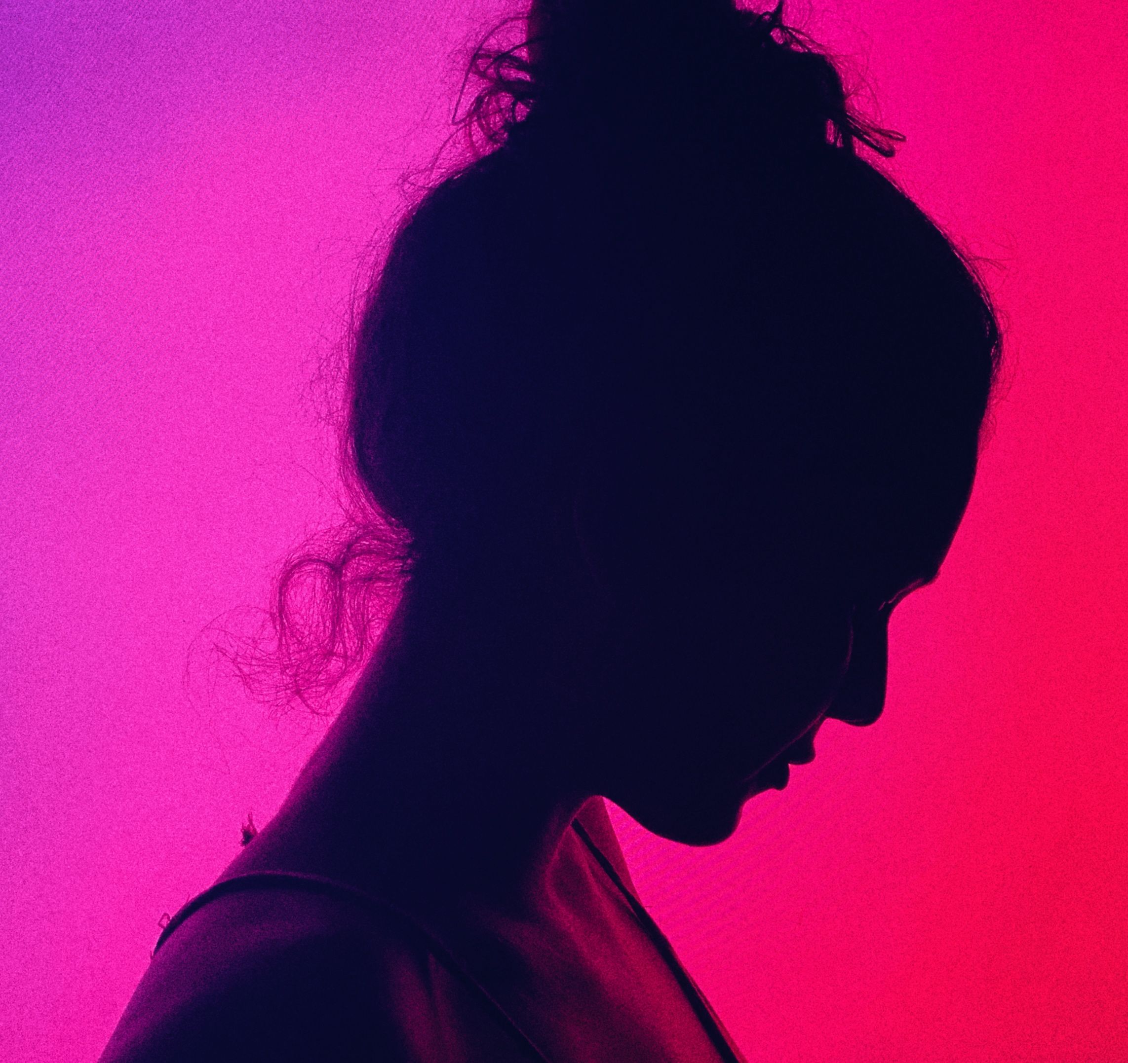 Side view of crop anonymous melancholic female with bun on head near colorful wall